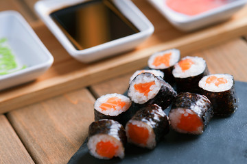 Sushi rolls with salmon and dishes with soy sauce, wasabi and ginger 