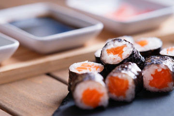 Sushi rolls with salmon and dishes with soy sauce and ginger 
