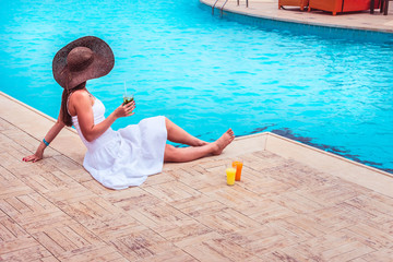The woman enjoying cocktail in a swimming pool