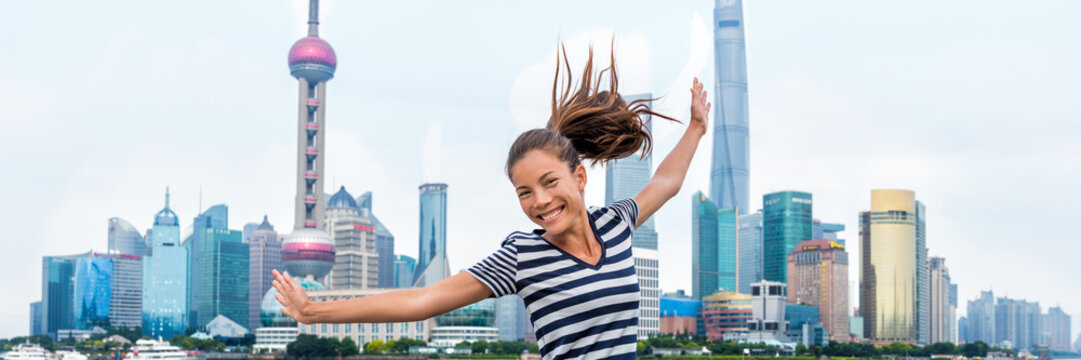 Happy Asian woman having fun dancing of joy in front of Shanghai skyline on The Bund. china travel healthy lifestyle. Happiness concept in urban city. Young adult in her 20s living active life.