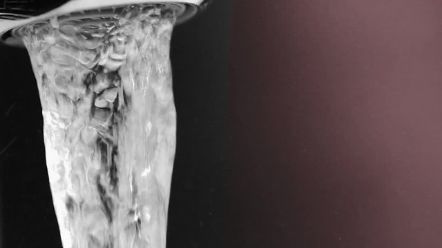 Water flows from a metallic tap close up