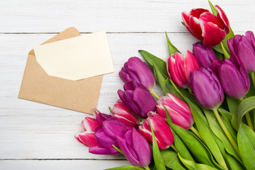Fototapeta premium Tulip bouquet and envelope on white wooden background, copy space