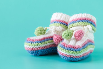 Fototapeta na wymiar Newborn announcement. knitted baby booties on plain blue background