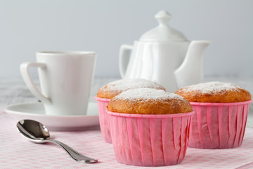 Breakfast with muffins sprinkled by powder sugar and coffee.