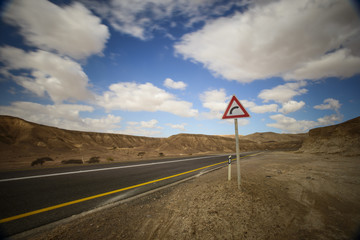 desert road with a curve sign