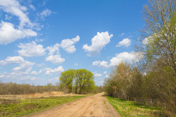 Fototapeta na wymiar Rural road with pits and blue sky with clouds