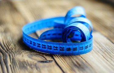 Blue measuring tape on wooden background