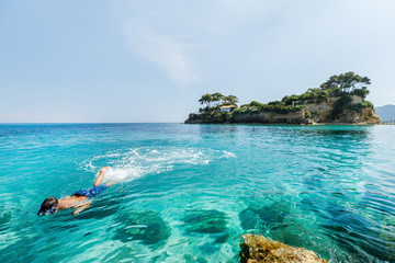 Boy snorkeling underwater in Ionian sea water at Zakinthos island in Greece. Zakinthos island popular summer Greek resort and travel destination with shallow turquoise water. Over water camera view.