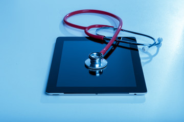 Stethoscope with tablet computer on blue background