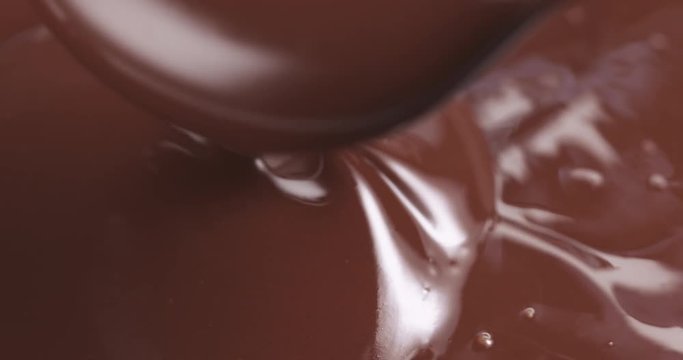 Slow motion of premium dark melted chocolate being poured from spoon in left part of frame, 4k 60fps prores footage