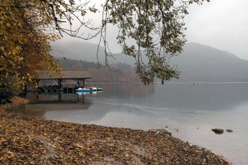 Hohenschwangau near Fussen in Bavaria, Germany. Boat station on the Alpsee lake surrounded by autumn forest.