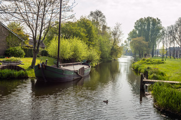 Fototapeta na wymiar Canal with ship in a small Dutch village