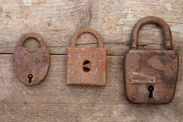 Three old rusty locks on wooden background