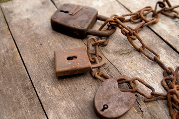 Three old rusty padlock and rusty chain on wooden background