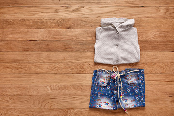 Children's jeans and jacket on wooden background.