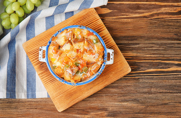 Freshly baked bread pudding in casserole dish on wooden board