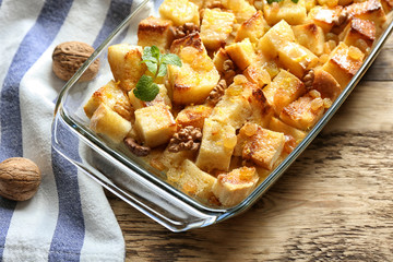 Delicious bread pudding with raisins in glass dish on wooden table