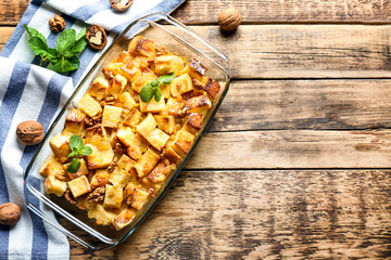 Delicious bread pudding with raisins in glass dish on wooden table