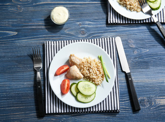 Plate with rice, chicken and vegetables on kitchen table