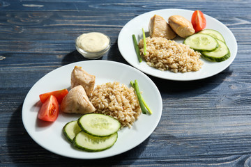 Plates with rice, chicken and vegetables on kitchen table