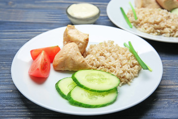 Plate with rice, chicken and vegetables on kitchen table
