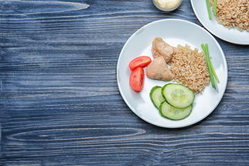Plate with rice, chicken and vegetables on kitchen table