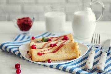 Plate with delicious pancakes and cranberry on table