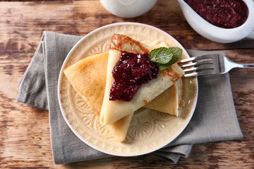 Plate with delicious pancakes and berry jam on table