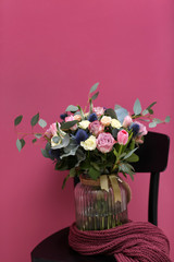 Wooden chair with beautiful bouquet on color background