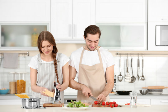 Young couple preparing pasta on kitchen table