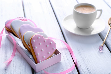 Heart shaped glazed cookies and cup of coffee on wooden background