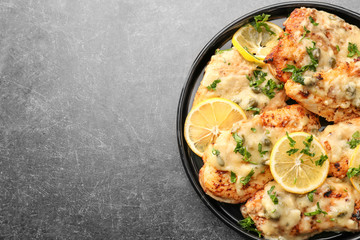 Plate with tasty Italian chicken piccata on table