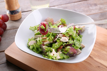 Plate with chicken salad and grapes on table