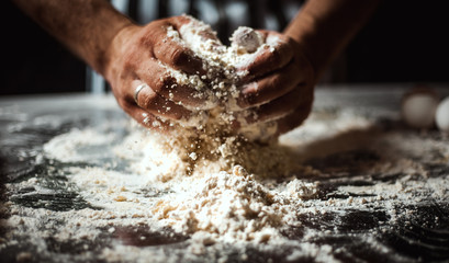 Man cooks dough on a glass table on a black background