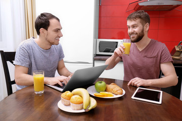 Fototapeta na wymiar Happy gay couple having breakfast in kitchen at home