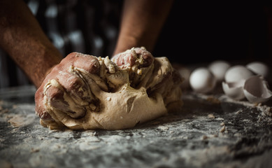 Man cooks dough on a glass table on a black background