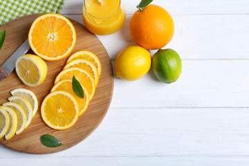 Board with sliced citrus fruits on wooden background