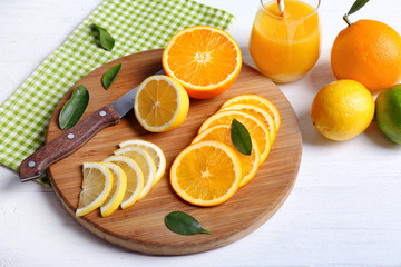 Board with sliced citrus fruits on wooden background