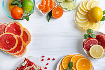Plates with different citrus fruits on white wooden background