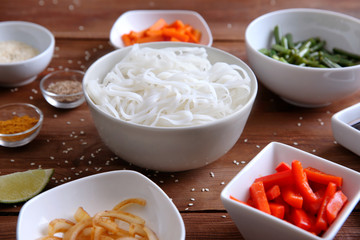 Ingredients for delicious rice noodles with vegetables on wooden table