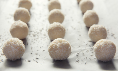 Tasty coconut candies on parchment, closeup