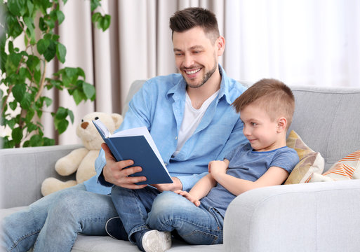 Dad and son reading interesting book at home