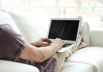 Handsome young man with laptop at home