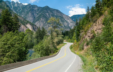 Scenic Road in British Columbia:  A winding tree-lined road passes a stream and rocky outcroppings...