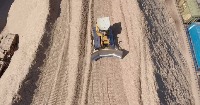 A yellow tractor on a mount of sawdust