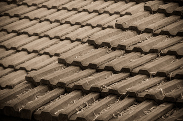 Earthenware roof of a building with leaves falling on it. Selective focus. Sepia tone. Vignetting effect.