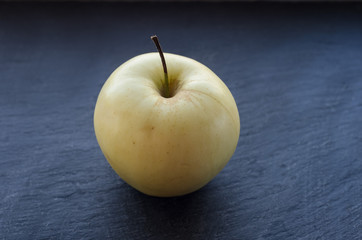 One yellow apple on a dark background