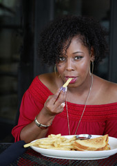 Beautiful African American woman with fancy manicure enjoying french fries