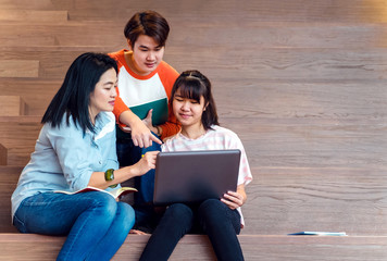 Groups of asian teenage students using laptop computer studying together at university stair library