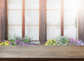 Wood table top and blurred flowers and window background with vintage filter